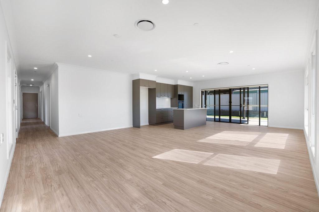 Large open-plan living area with timber-look floors, a kitchen with island bench, and sliding doors to the patio.