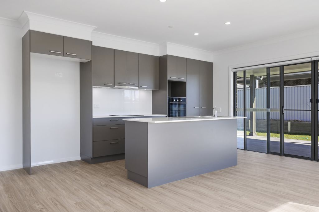 Kitchen with grey cabinetry, a stone-topped island bench and sliding doors to the covered patio.